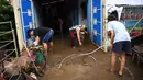 Warga membersihkan rumah mereka setelah banjir akibat Topan Goni yang melanda Kota Batangas di selatan Manila, Filipina, Senin (2/11/2020). Goni, sebuah topan kategori 5 yang disebut-sebut sebagai topan terkuat sepanjang 2020, menghantam Filipina pada Minggu, 1 November 2020. (TED ALJIBE / AFP)
