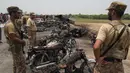 Petugas keamanan Pakistan berjaga di dekat bangkai kendaraan yang terbakar akibat ledakan truk tangki minyak di jalan raya dekat Bahawalpur, Pakistan (25/6). (AFP Photo/SS Mirza)