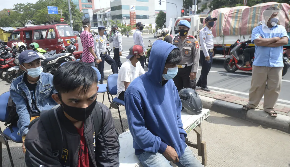 Pengendara yang terjaring razia masker antre untuk didata di Jalan Panjang, Kedoya, Jakarta Barat, Senin (2812/2020). Pengendara yang tidak mengenakan masker langsung menjalani rapid test antigen gratis untuk mencegah penularan COVID-19. (merdeka.com/Dwi Narwoko)