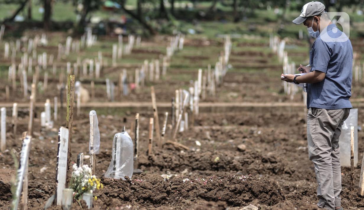 Petugas mendata makam pasien Covid-19 di TPU Bambu Apus, Jakarta, Selasa (2/3/2021). TPU Bambu Apus kini tidak lagi menampung pemakaman jenazah protokol Covid-19 akibat lahan di dua blok sudah penuh dan dialihkan ke TPU Srengseng Sawah. (merdeka.com/Iqbal S Nugroho)