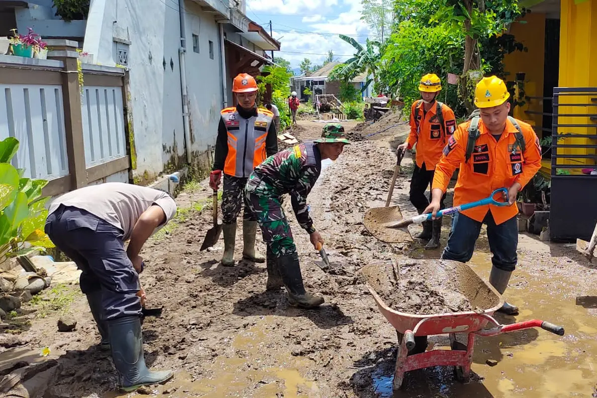 Petugas membersihkan lumpur sisa banjir di Jember. (Dian Kurniawan/Liputan6.com)