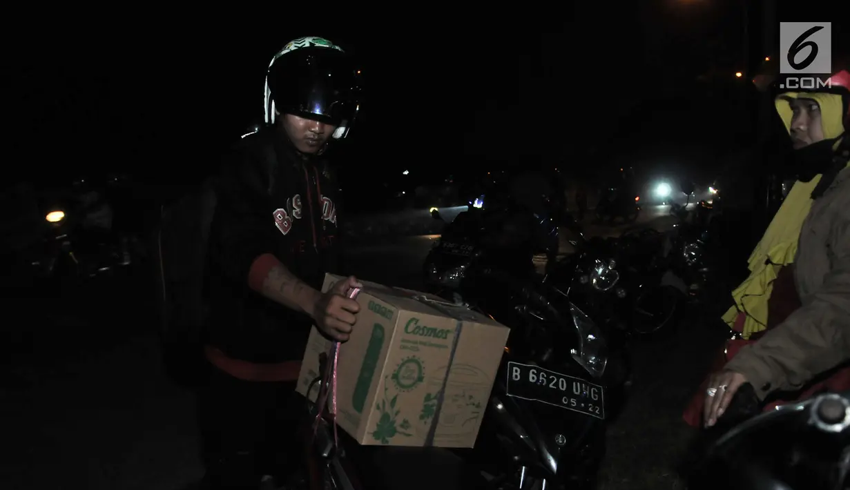 Pemudik sepeda motor memperbaiki barang bawaan saat mudik melintasi ruas jalan Kalimalang, Bekasi, Jawa Barat, Minggu (2/7) malam. Pos Pengamanan Simpang BCP Bekasi mencatat pada Minggu (2/7) malam terdapat 5.739 sepeda motor melintasi jalur mudik via Kalimalang. (merdeka.com/Iqbal S. Nugroho)