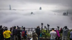 Orang-orang mengambil foto kabut di atas Hong Kong, Selasa (22/3/2022). Kabut tebal menyelimuti Hong Kong pada musim semi ketika wilayah tersebut dipengaruhi oleh udara dingin dan hangat bergantian. (AFP/Dale De La Rey)