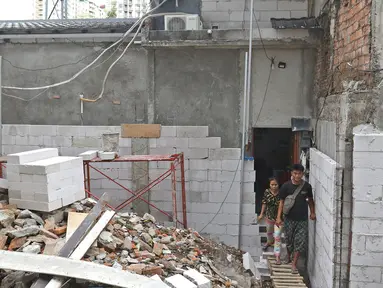 Salah satu kerabat pemilik rumah saat keluar dari rumah di kawasan Mangga Dua Dalam, Jakarta, Kamis (12/12/2019). Sebuah rumah di kawasan Mangga Dua terhimpit oleh bangunan yang sedang dibangun. (Liputan6.com/Herman Zakharia)