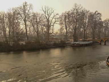 Tukang perahu menggunakan dayung memecahkan lapisan es di sepanjang bagian dalam Danau Dal pada pagi saat musim dingin di Srinagar (2/1/2023). Periode musim dingin yang keras selama 40 hari yang dikenal sebagai 'Chillai Kalan' memperketat cengkeramannya di Kashmir pada hari Senin karena suhu malam semakin turun. (AFP/Tauseef Mustafa)