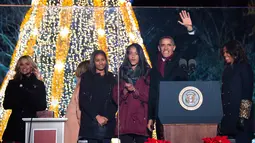 Presiden AS Barack Obama (kedua kanan) melambaikan tangan ke ribuan warga saat akan menyalakan Pohon Natal Nasional di Taman Ellipse, dekat Gedung Putih, Washington, Kamis (3/12). Acara tersebut menandai dimulainya musim Natal. (AFP PHOTO/JIM WATSON)