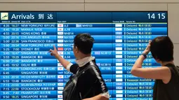 Penumpang melihat papan informasi penerbangan kedatangan di Terminal Internasional Bandara Haneda setelah penerbangan dibatalkan atau ditunda karena badai tropis Jangmi di Tokyo, Jepang, Rabu 3 Juni 2026. (Andrew CAALLERO-REYNOLDS/AFP)