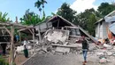 Penduduk desa berjalan di depan rumah yang roboh akibat gempa di desa Sajang, Sembalun, Lombok Timur, Minggu (29/7). Data sementara mencatat, gempa bumi tektonik 6.4 SR itu mengakibatkan 10 orang meninggal dunia dan puluhan rumah rusak. (AP/Rosidin)