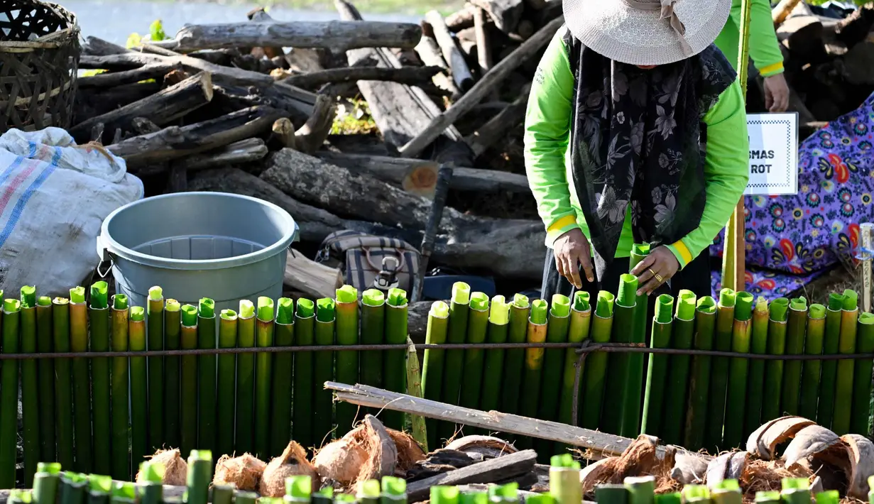 Seorang peserta bersiap memasak lemang, hidangan nasi ketan tradisional yang dimasukkan ke dalam tabung bambu dan diisi dengan santan yang kemudian diletakkan di atas api, selama acara memasak massal di Blang Pidie, Kabupaten Aceh Barat Daya, Aceh, pada Sabtu 25 April 2026. (CHAIDEER MAHYUDDIN/AFP)