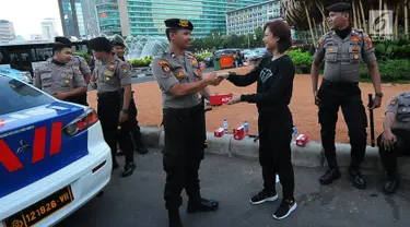 Relawan TKN Jokowi-Ma'ruf Amin membagikan makanan berbuka puasa kepada aparat kepolisian yang melakukan penjagaan di kawasan Bundaran HI, Jakarta, Jumat (24/5/2019). Kegiatan ini sebagai bentuk kepedulian untuk aparat yang telah menjaga keamanan di Jakarta. (Liputan6.com/Angga Yuniar)