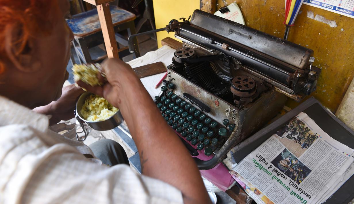 Seorang juru ketik makan siang di kios ketik pinggir jalan di Mumbai, India (6/7). Sekitar 3.500 institut di negara bagian Maharashtra  yang masih menggunakan mesin tik manual akan diganti dengan teknologi komputer. (AFP Photo/Indranil Mukherjee)