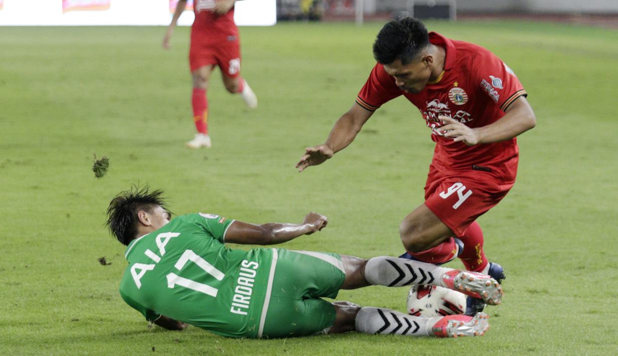 Penyerang Persija Jakarta, Heri Susanto, terjatuh saat berebut bola dengan pemain Geylang International FC, Firdaus Kasman, pada laga uji coba di SUGBK, Jakarta, Minggu, (23/2/2020). Persija menang dengan skor 3-1. (Bola.com/M Iqbal Ichsan)