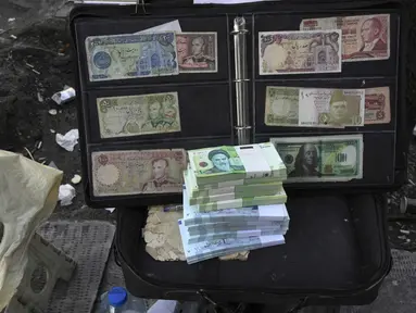 Uang kertas dan mata uang asing Iran saat ini dan sebelum revolusi ditampilkan oleh seorang penjual di distrik komersial di pusat kota Teheran, Minggu (26/2/2023). Mata uang Iran jatuh ke rekor terendah yang baru pada hari Minggu (26/2), yaitu anjlok ke 600.000 per 1 dolar Amerika, untuk pertama kalinya lantaran dampak terus berlangsungnya demonstrasi anti-pemerintah dan gagalnya upaya menghidupkan kembali perjanjian nuklir tahun 2015 yang terus menggerus ekonomi. (AP Photo/Vahid Salemi)