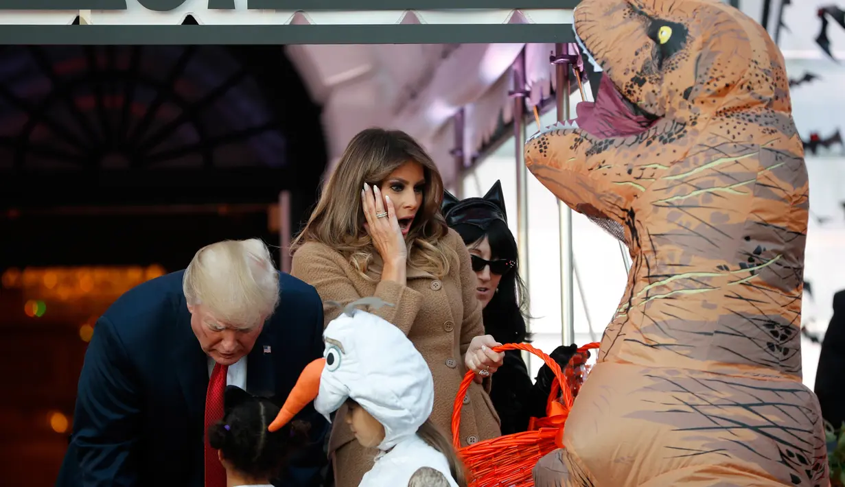 Reaksi Ibu Negara, Melania Trump ketika melihat seorang anak berkostum dinosaurus saat open house perayaan pesta Halloween di Gedung Putih, Senin (30/10). Selain ratusan siswa, keluarga militer juga hadir di acara itu. (AP/Pablo Martinez Monsivais)