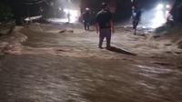 Aliran sungai meluap ke jalan raya di Desa Jelun Banyuwangi, akibat intensitas hujan yang cukup lebat yang menyebabkan akses jalan dari kota Banyuwangi menuju kawasan wisata Kawah Ijen lumpuh pada Kamis malam (22/5/2025) (Istimewa)