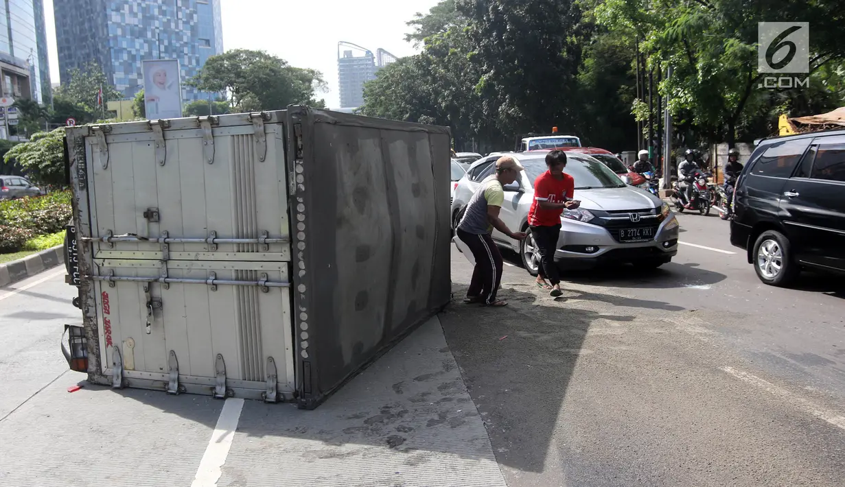 Sebuah mobil boks terguling di Jalan Casablanca, Jakarta, Rabu (27/6). Mobil bernomor polisi B 9515 FCC terguling setelah menabrak pembatas jalan. (Liputan6.com/Arya Manggala)