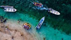 Pemandangan udara menunjukkan orang-orang saat berkumpul menikmati masa libur panjang Idulfitri di area olahraga air, Pantai Lhoknga, Aceh, pada Kamis 26 Maret 2026. Libur perayaan Idulfitri 1447 Hijriah memberi kesempatan panjang bagi warga Aceh untuk berwisata, salah satunya ke Pantai Lhoknga. (Chaideer MAHYUDDIN/AFP)