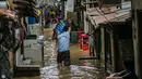 Seorang pria menyusuri banjir yang merendam permukiman di kawasan Kampung Melayu, Jakarta, Selasa (9/2/2021). Banjir yang berangsur surut dimanfaatkan warga untuk membersihkan rumah dan barang-barang dari endapan lumpur. (Liputan6.com/Faizal Fanani)