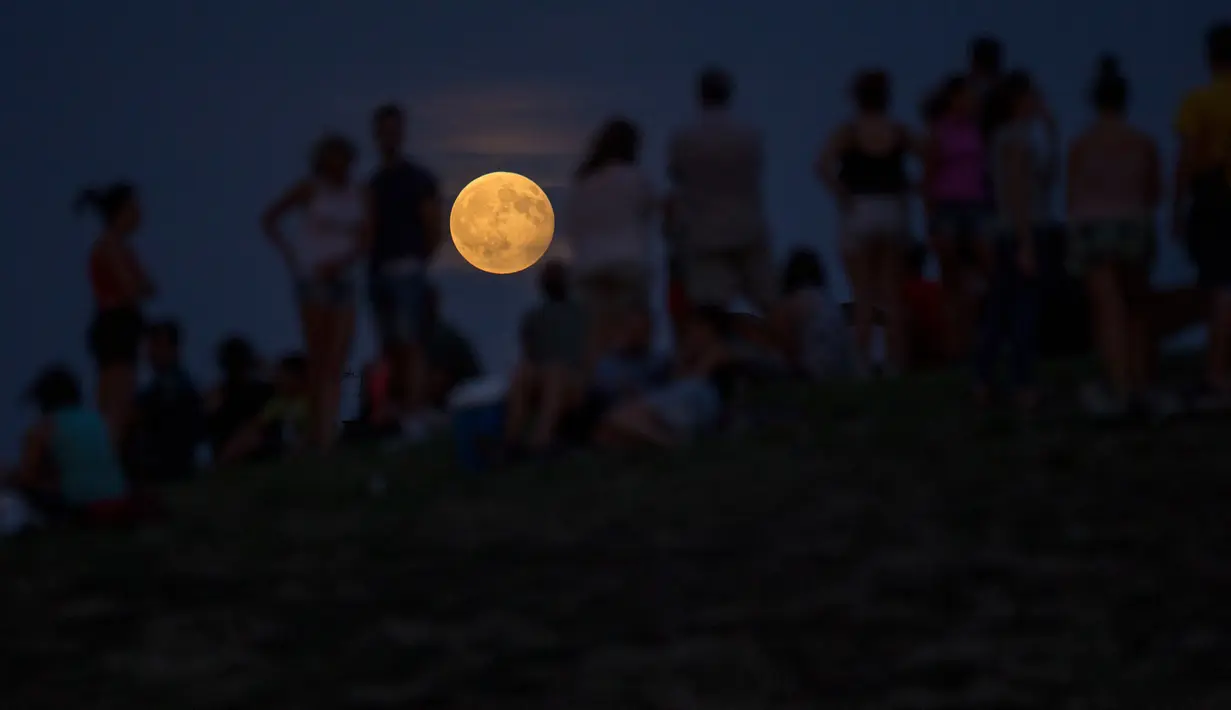 Sejumlah orang menyaksikan gerhana bulan parsial dari atas sebuah bukit di taman Tio Pio, Madrid, Senin (7/8). Gerhana bulan parsial terjadi ketika bumi bergerak di antara bulan dan matahari, tapi tidak persis dalam satu garis. (AP Photo/Francisco Seco)