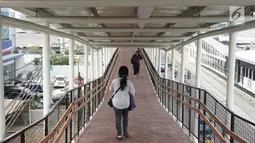 Warga melintasi jembatan penyeberangan (Skybridge) yang menghubungkan Stasiun LRT Velodrome dengan Halte Transjakarta Pemuda di Rawamangun, Jakarta, Senin (29/7/2019). Skybridge berdesain artistik tersebut memiliki panjang sekitar 500 meter dan lebar 2 meter. (Liputan6.com/Immanuel Antonius)