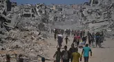 Pengungsi Palestina berjalan melewati bangunan-bangunan yang hancur saat mereka kembali ke rumah mereka di kawasan Zeitoun, Kota Gaza, pada Jumat 10 Oktober 2025, setelah Israel dan Hamas sepakat untuk menghentikan sementara perang mereka dan membebaskan sandera yang tersisa. (AP Photo/Jehad Alshrafi)