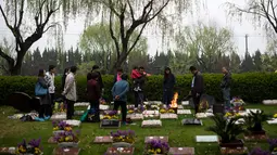 Sebuah keluarga membakar dupa saat mengunjungi pemakaman pada festival tahunan Qingming (Cheng Beng) di Shanghai, Minggu (3/4). Festival ini merupakan hari ziarah kubur ditandai dengan mengunjungi dan membersihkan kuburan leluhur. (Johannes EISELE/AFP)