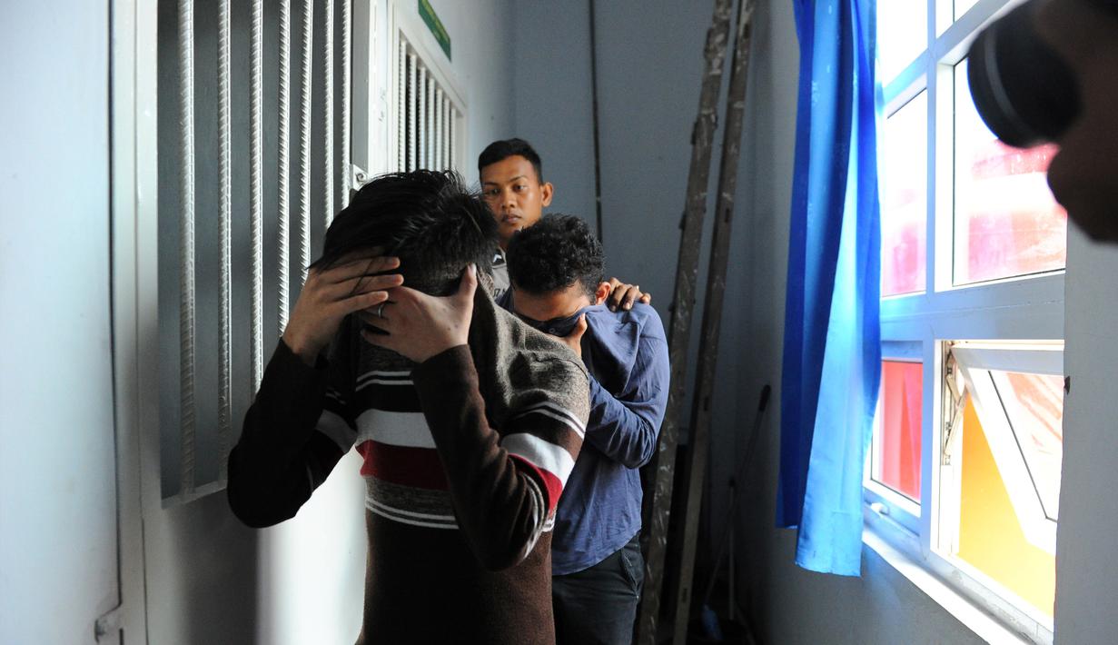 Terdakwa pasangan sejenis (gay) menutupi wajahnya saat dibawa untuk menjalani persidangan di pengadilan syariah di Banda Aceh (17/5). Majelis hakim Mahkamah Syar'iyah Banda Aceh memvonis terdakwa dengan 85 kali cambuk. (AFP/Chaideer Mahyuddin)