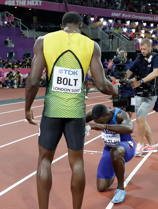 Pelari AS, Justin Gatlin berlutut di hadapan Usain Bolt usai menjadi juara pada lomba lari 100 meter Kejuaraan Dunia Atletik 2017 di Stadion London, Minggu (6/8). Itu dilakukan usai Gatlin dicemooh para penonton karena menjadi juara (AP/Matthias Schrader)