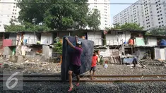 Warga membawa kasur saat alat berat merobohkan bangunan rumah mereka di kawasam Rawajati, Jakarta, Kamis (1/9). Penertiban tersebut menyebabkan warga terpaksa menyelamatkan barang berharga mereka ke tepi rel kereta api. (Liputan6.com/Immanuel Antonius)