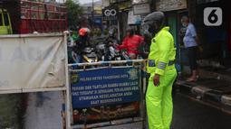 Petugas kepolisian melakukan penutupan jalan KH Hasyim Ashari, Kota Tangerang, Banten, Sabtu (16/7/2022). Intensitas curah hujan yang tinggi sejak Jumat (15/7) siang menyebabkan akses jalan Hasyim Ashari terputus karena terendam banjir setinggi 50 hingga 70 sentimeter. (Liputan6.com/Angga Yuniar)