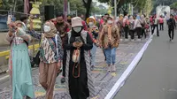 Sejumlah orang yang mengenakan batik mengambil gambar menggunakan gadgetnya saat berjalan di catwalk sepanjang Jalan Jenderal Sudirman, Jakarta, Minggu (2/10/2022). Kegiatan yang diikuti ratusan orang ini diselenggarakan oleh Bank Mandiri untuk menyambut Hari Batik Nasional yang jatuh setiap tanggal 2 Oktober 2022. (Liputan6.com/Faizal Fanani)