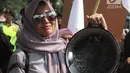 Seorang ibu dari Barisan Emak-Emak Militan Indonesia membawa wajan saat menggelar aksi di seberang Istana Merdeka, Jakarta, Rabu (18/7). Dalam aksinya, emak-emak ini  membawa peralatan memasak seperti penggorengan dan panci. (Liputan6.com/Arya Manggala)