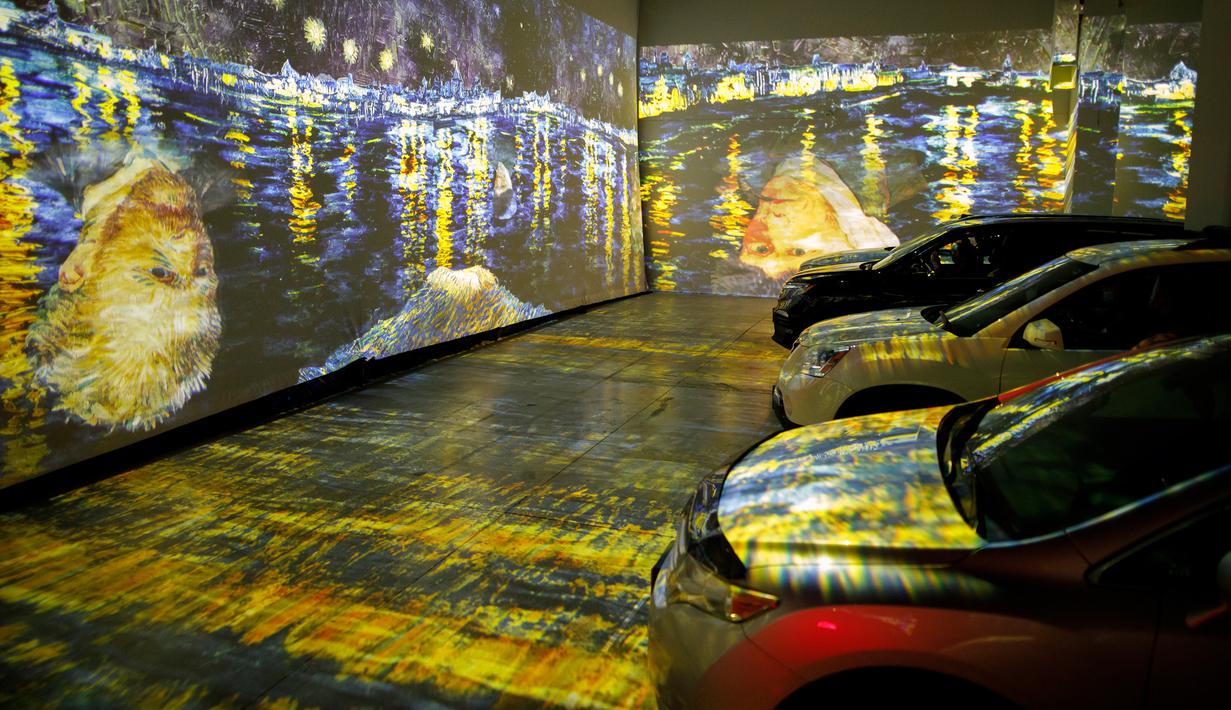 Orang-orang duduk di mobil mereka menikmati pameran seni Vincent Van Gogh di Toronto, Ontario, Kanada pada 3 Juli 2020. Pameran seni di masa pandemi Covid-19 mendatangkan ide kreatif para penyelenggara kegiatan dengan memamerkan hasil karya seni lewat konsep drive-in. (Cole BURSTON/AFP)