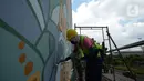 Muralis perempuan menyelesaikan pembuatan mural pada dinding di kawasan Juanda, Jakarta, Rabu (16/6/2021). Cat yang digunakan setara dengan kemampuan pohon menyerap zat polutan/berbahaya sekaligus membersihkan udara. (merdeka.com/Imam Buhori)