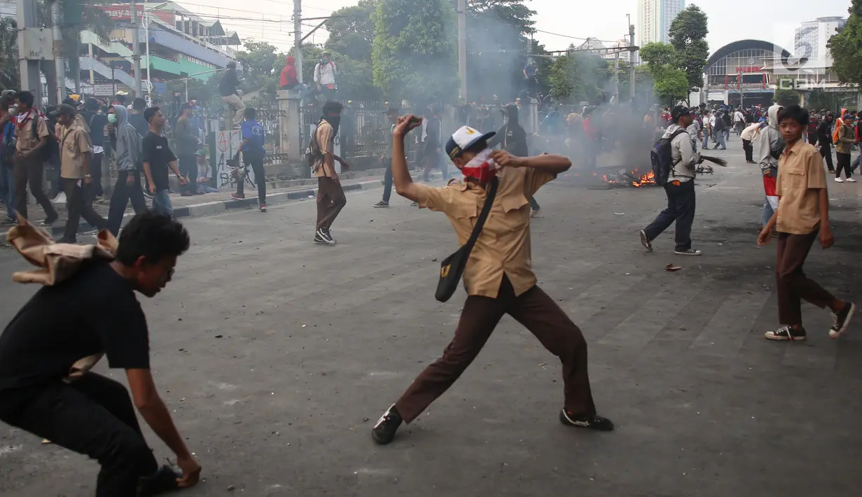 Pelajar melempari Gedung DPR dengan batu saat berunjuk rasa di Palmerah, Jakarta, Rabu (25/9/2019). Pihak kepolisian menembakan gas air mata untuk memukul mundur pelajar. (Liputan6.com/Angga Yuniar)