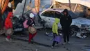 Anak-anak Palestina membawa barang-barang yang dapat diselamatkan berjalan di tengah kehancuran yang disebabkan oleh serangan Israel terhadap kamp pengungsian sementara di Mawasi Khan Yunis, Jalur Gaza selatan pada tanggal 2 Januari 2025. (BASHAR TALEB/AFP)