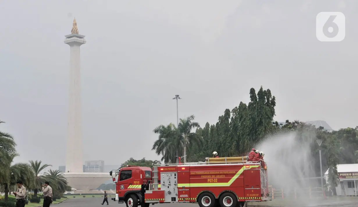 Petugas pemadam kebarakan menyemprotkan cairan disinfektan di kompleks Monumen Nasional (Monas), Jakarta, Senin (30/3/2020). Penyemprotan disinfektan ini dilakukan guna memutus rantai penyebaran virus Corona atau Covid-19 di pusat kota. (merdeka.com/Iqbal S. Nugroho)