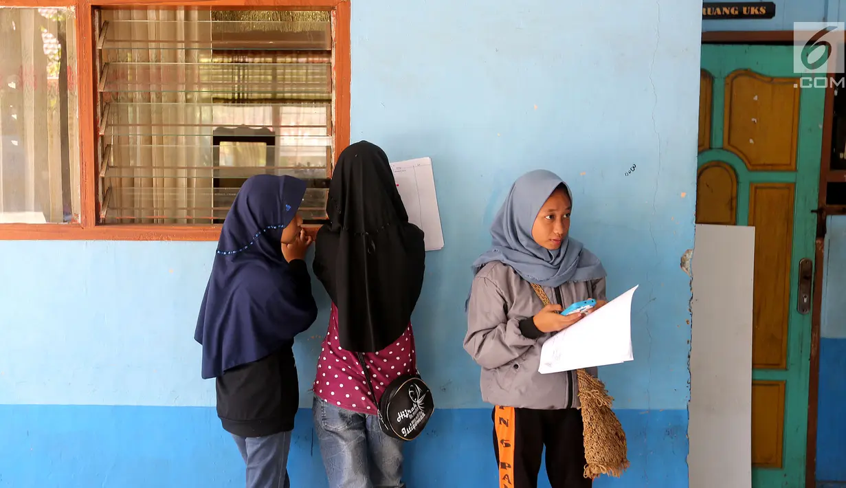 Sejumlah siswi melakukan pendataan pada hari pertama sekolah di SMP Negeri 6 Palu, Sulawesi Tengah, Senin (8/10). Pascagempa dan tsunami Palu, pihak sekolah melakukan pendataan untuk mengetahui jumlah siswa sekolah. (Liputan6.com/Fery Pradolo)