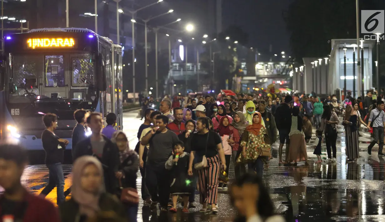 Warga menikmati car free night saat malam pergantian tahun di Jalan MH Thamrin, Jakarta, Senin (31/12). Hujan yang mengguyur Jakarta sejak siang tidak menyurutkan antusias warga menikmati car free night. (Liputan6.com/Angga Yuniar)