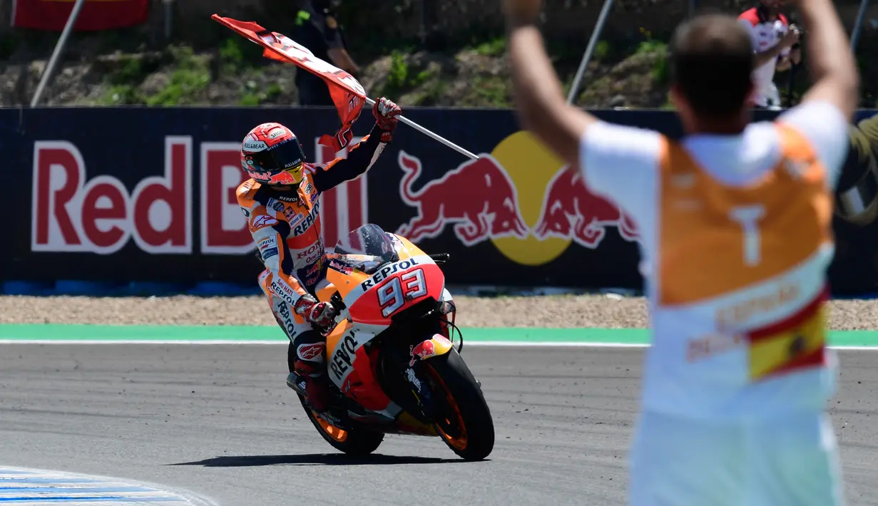 Pembalap Repsol Honda, Marc Marquez membawa bendera saat berselebrasi usai memenangi balapan MotoGP Spanyol 2018 di Sirkuit Jerez, Minggu (6/5). Marquez mengukir waktu 41 menit 39,678 detik. (AFP Photo/ JAVIER SORIANO)