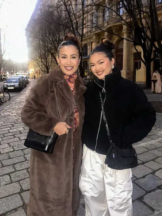 Berada di Vienna, Austria Liza Natalia mengenakan jaket coklat berbulu dipadukan inner turtleneck bunga. Sedangkan putrinya tampil mengenakan atasan jaket crop hitam dipadukan celana putih cargo.  [@lizanataliaofficial]