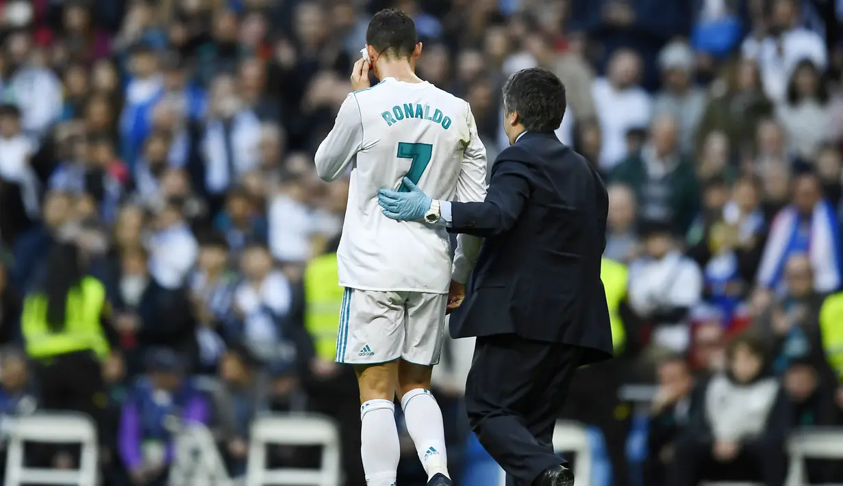 Striker Real Madrid, Cristiano Ronaldo, keluar lapangan saat mengalami pendarahan di bagian pelipis pada laga La Liga di Stadion Santiago Bernabeu, Minggu (21/1/2018). Real Madrid menang 7-1 atas Deportivo La Coruna. (AFP/Oscar Del Pozo)