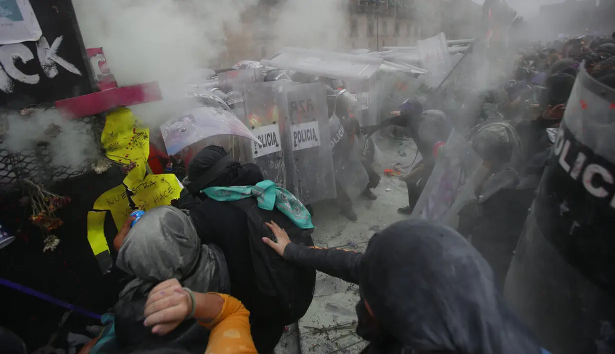 Demonstran bentrok dengan polisi yang melindungi Istana Nasional selama pawai untuk memperingati Hari Perempuan Internasional dan protes terhadap kekerasan gender di Mexico City, Meksiko, Senin (8/3/2021). Hari Perempuan Internasional diperingati setiap tanggal 8 Maret. (AP Photo/Ginnette Riquelme)