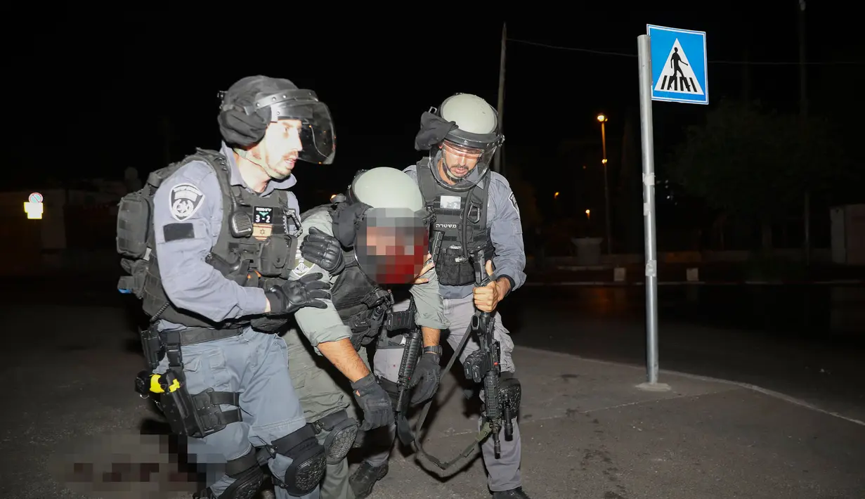 Seorang petugas polisi Israel yang terluka dibantu selama bentrokan dengan pengunjuk rasa Palestina, di Yerusalem timur (7/6/2021). Warga Palestina memprotes atas ancaman penggusuran Israel atas puluhan warga Palestina di lingkungan Sheikh Jarrah. (AP Photo/Mahmoud Illean)