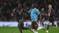 Gelandang Timnas Inggris, Kobbie Mainoo, berebut bola dengan gelandang Timnas Belgia, Jeremy Doku, dalam laga uji coba internasional di Wembley, London, Rabu (27/3/2024). (Adrian DENNIS / AFP)