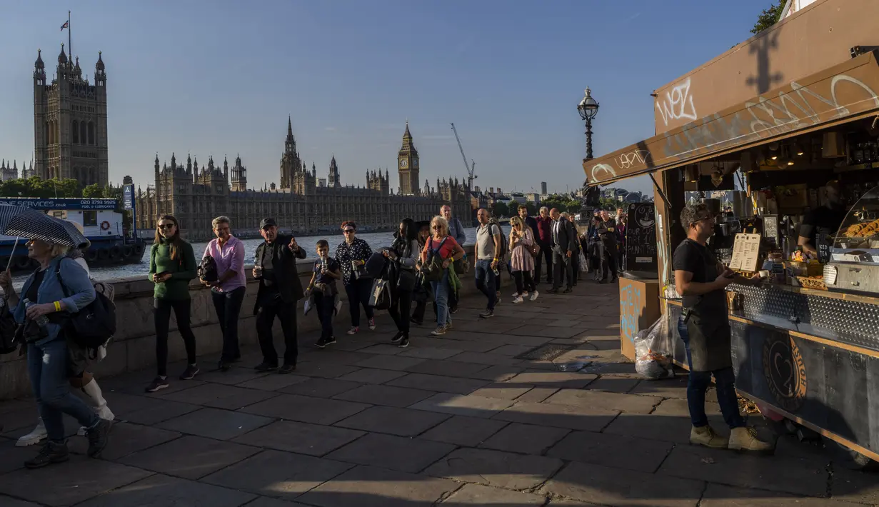 Seorang pria membeli dari vendor saat orang mengantre untuk memberi penghormatan kepada mendiang Ratu Elizabeth II yang terbaring di Westminster Hall London, pada 14 September 2022. Ratusan ribu orang diperkirakan akan memberikan penghormatan kepada ratu menjelang pemakaman kenegaraannya, mendorong permintaan kamar hotel di pusat kota London yang dalam beberapa kasus harganya naik dua kali lipat. (AP Photo/Bernat Armangue, File)