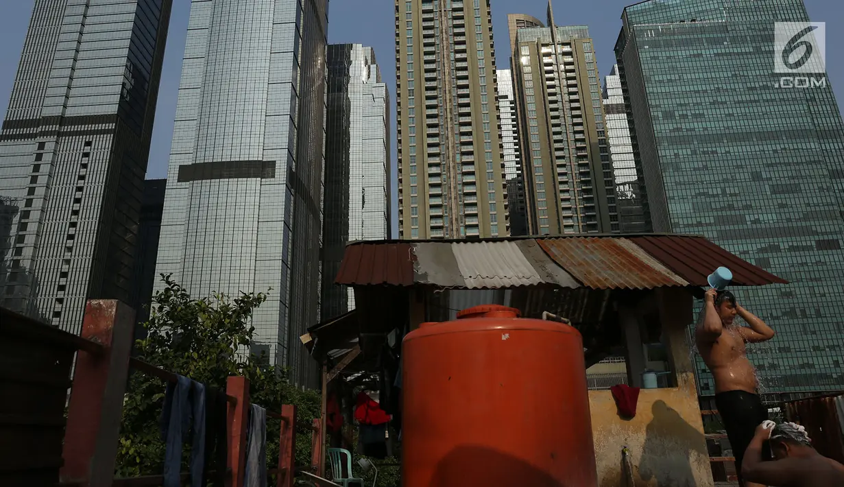 Seorang warga beraktivitas di sebuah permukiman di antara gedung-gedng bertingkat kawasan Senayan, Jakarta, Jumat (28/9). Rumah-rumah kecil Ibu Kota makin tersingkir dikarenakan banyaknya lahan yang dijadikan kawasan komersial. (Merdeka.com/Imam Buhori)