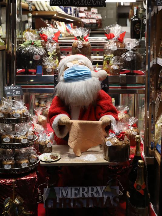 Mainan Sinterklas yang memakai masker di sebuah toko roti di Roma, Italia (14/12/2020). Berbagai pernak-pernik dan aksesoris menghiasi kota Roma menyambut Natal. (Xinhua/Cheng Tingting)