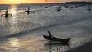 Seorang nelayan membawa perahunya untuk pergi memancing ikan di Kedonganan, Denpasar, Bali (15/7/2019). Batas wilayah Kelurahan Kedonganan terletak di ujung utara Kecamatan Kuta. (AFP Photo/Sonny Tumbelaka)