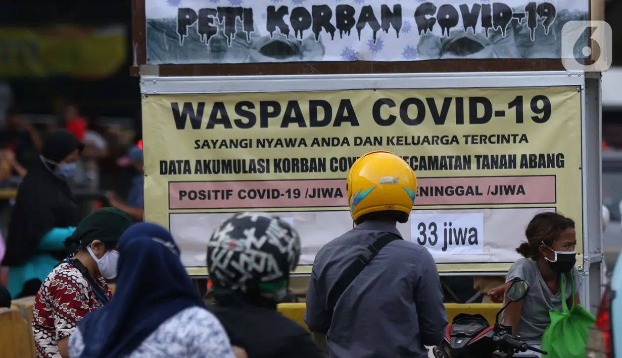 Warga melihat tanda peringatan bahaya COVID-19 di sekitar Pasar Blok A Tanah Abang, Jakarta, Selasa (1/9/2020). Guna meningkatkan kewaspadaan masyarakat, muspida kecamatan Tanah Abang memajang peti mati dilengkapi data jumlah korban COVID-19 di wilayah tersebut. (Liputan6.comHelmi Fithriansyah)